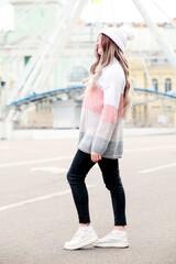 Outdoors lifestyle fashion portrait of stunning blonde young woman. Wearing stylish pullover, knitted hat.