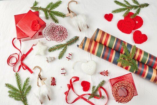 Christmas background with gift boxes, ribbon, twine, paper rolls, knitted hearts and Christmas ornament.