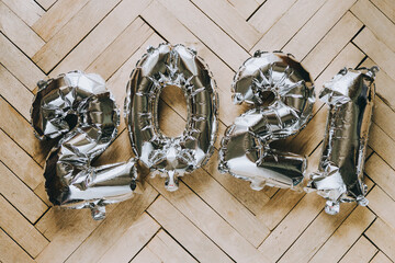 Inscription 2021 from inflatable silver balls on the background of wooden parquet. New year's eve 2021, festive mood.