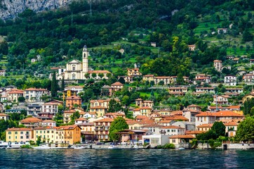 View of village in forest in Lake Como from ferry at sunset, chu