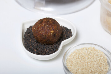 Dried fruit and nuts candy. Made at home in isolation during the epidemic. Lies on black sesame seeds.