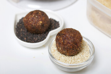 Dried fruit and nut sweets. Made at home in self-isolation during the epidemic. They lie on black and white sesame seeds.