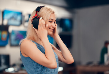 Beautiful smiling girl is testing new headphones in the electronics store. © Olena Apetroaiei