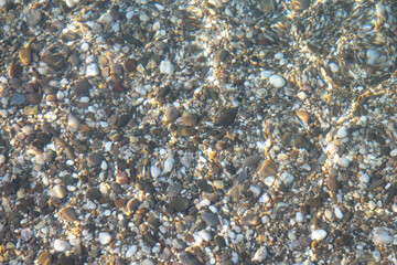The bottom is made of small stones under water. Pure clear water with sun glare. A wonderful background for relaxation.