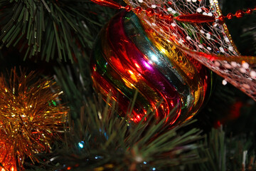 Christmas colored Christmas ball decorates the tree. Christmas ball and ribbon close-up on the tree.