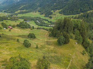 Aerial view of Goms valley in Switzerland from above during summer. Green forest on mountain slopes in Swiss alps.