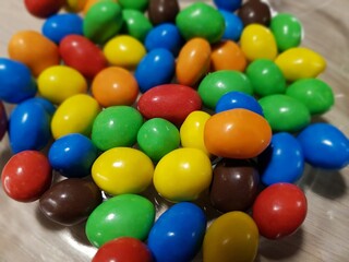 Fototapeta na wymiar Multicolored chocolate-covered nuts in a transparent plate