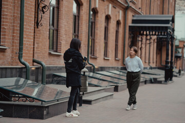 Fototapeta premium Young female photographer strolling along alley with girlfriend. Travelers walk in the city. Look attractions city.