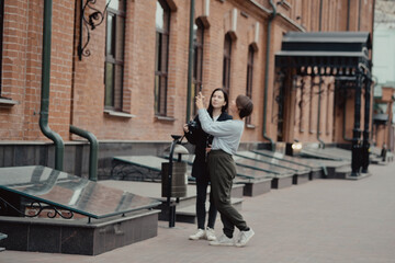 Young female photographer strolling along alley with girlfriend. Travelers walk in the city. Look attractions city.