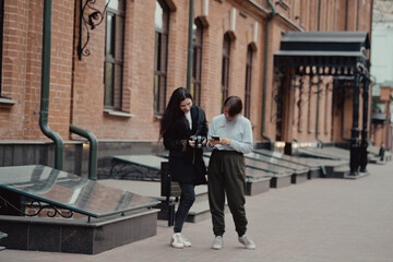 Young female photographer strolling along alley with girlfriend. Travelers walk in the city. Look attractions city.