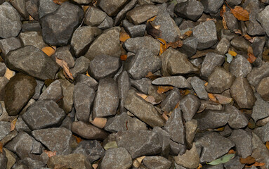 Seamless background of wet stones lying in a jumble with yellow leaves