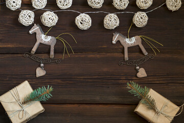 Christmas wooden toys rocking horse, gift boxes in craft paper, a garland from natural material on a dark wooden background. New Year concept. Top view. Copy space