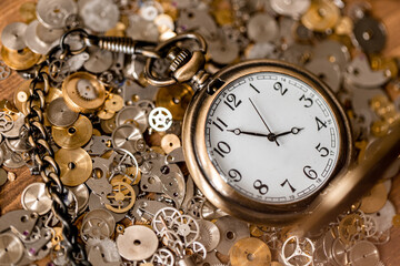 Pocket watch sitting on a bunch of gears and watch pieces