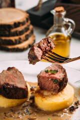 Eating beef medallion on corn porridge with sauce