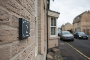 Shallow focus of generic town house number signs seen attached the to outside wall, near the...