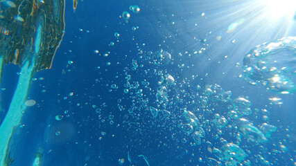 Fototapeta na wymiar Underwater bubbles emerging to turquoise sea surface