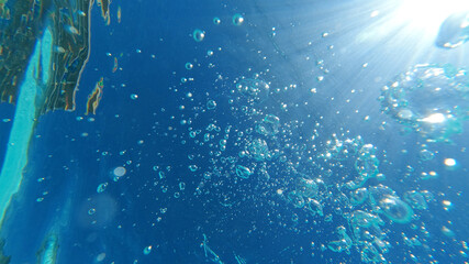 Fototapeta na wymiar Underwater bubbles emerging to turquoise sea surface