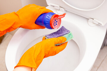 Man or woman pours cleaning agent on sponge. Cleaning the toilet. Concept of household responsibilities