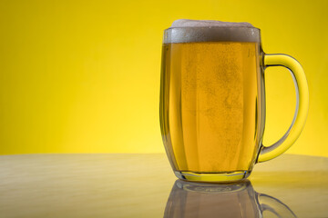 A glass of light beer on a yellow background.