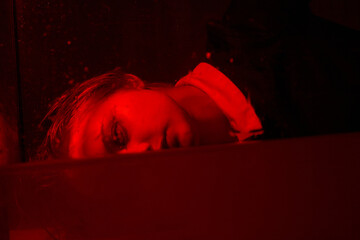 Horrible portrait of a young girl in a horror room with a red light.
