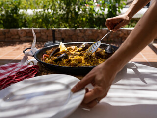 hands serving a spanish paella
