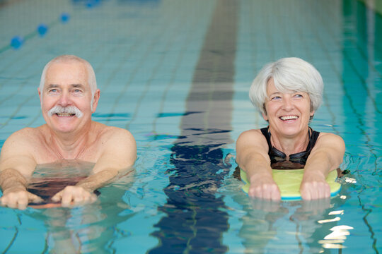 senior couple exercising with floats in swimming pool