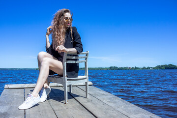 Fototapeta premium A girl in a black jacket against the background of the Uglich reservoir Kalyazin city. Rocky shore.