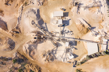Aerial view of a large Quarry during work hours with Stone sorting conveyor belts and a truck passing.
