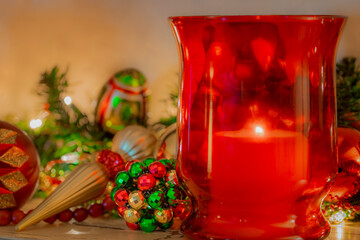 Christmas mantelpiece with red and green  ornaments and red glass candle holder