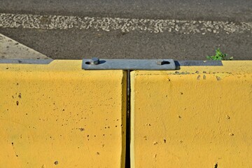 Two yellow concrete blocks connected by a steel coupling. Jersey barrier, Jersey wall, modular...