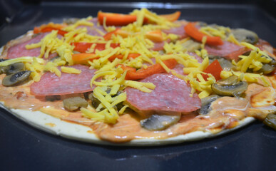 Homemade pizza with tomatoes, sauce, mayonnaise, pepper, cheese, mushrooms, salami sausage