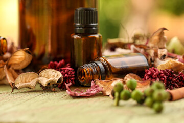 Selection of various sized amber bottles on wooden surface with dried flowers and leaves. Rustic wellness image.