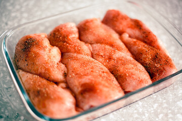 Raw Chicken fillets with spice in glass baking tray