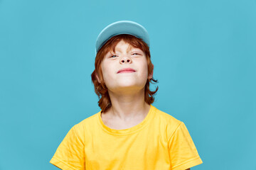 Redhead boy with head raised smile blue cap yellow t-shirt 