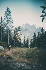 Fototapeta na wymiar A young caucasian woman backpacker walking on a rocky road towards a mountain