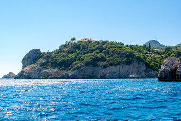 Fototapeta na wymiar A view of a monastery atop a cliff in Palaiokastritsa, Corfu, as seen from a boat