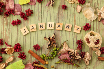 Flat lay image featuring border of various dried flowers surrounding wooden letters spelling the word January with copy space