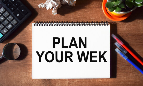 The inscription PLAN YOUR WEK written in a notebook, against the background of office supplies. Top view of the desktop. Business concept.