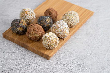 Homemade energy balls with dried fruits , nuts, sesame seeds, cocoa, almonds and poppy seeds on a wooden Board, light background. Vegan and vegetarian raw appetizer or food. copy of the space.