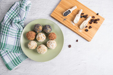 Homemade energy balls with dried fruits, nuts, sesame seeds, cocoa, almonds and poppy seeds on a plate, light background. Vegan and vegetarian raw appetizer or food. Close up.