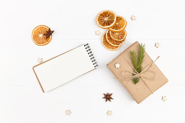 Fototapeta na wymiar Creative layout with gift box, christmas spices, oranges and blank notepad on white background.