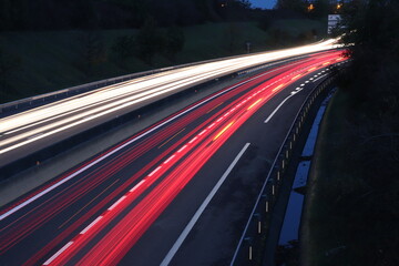 Fototapeta na wymiar Trainées de lumières de phares de voitures au coucher du soleil sur le boulevard urbain sud de Lyon, ville de Corbas, département du Rhône, France