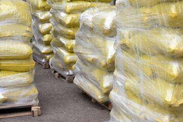 bags with building material are stacked on pallets and wrapped in stretch wrap.