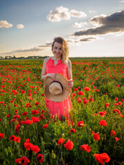 Young girl in a red dress in a poppy field
