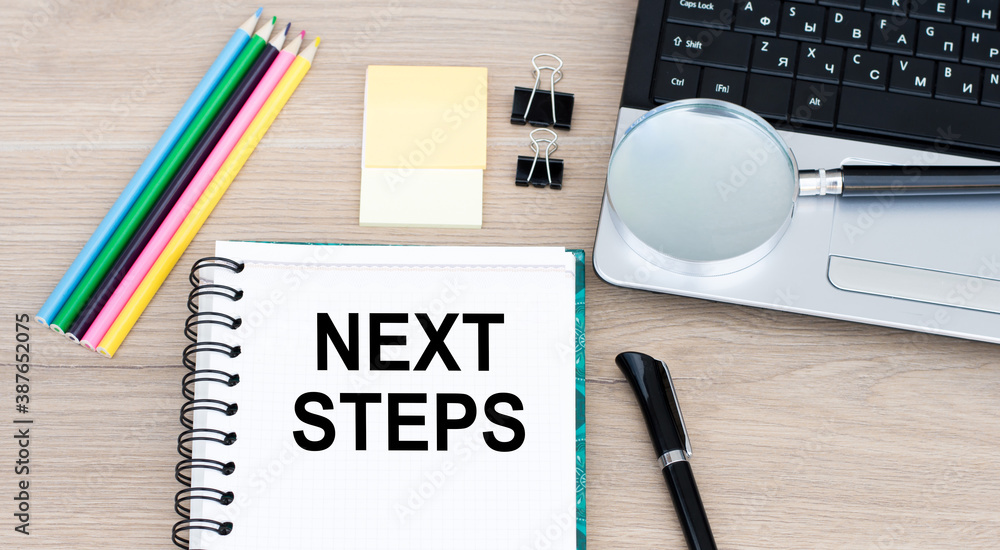 Poster next steps text on notepad on office desk. business concept