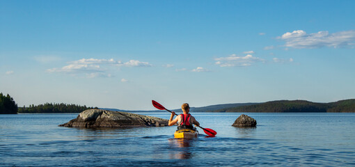 Kanu Paddler auf einem See in Schweden zwischen Felsen