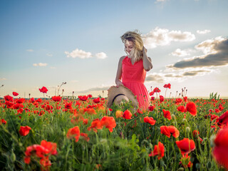 Young girl in a red dress in a poppy field
