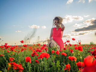 Young girl in a red dress in a poppy field
