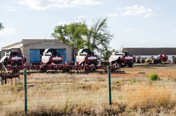 agricultural machinery, harvesters, harrows are behind the fence