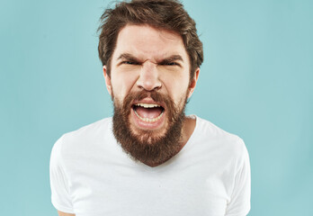 Aggressive man with a beard on a blue background cropped view